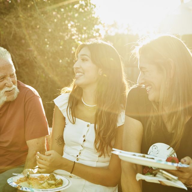 labor date quotes two laughing women holding plates of food and talking to older man while all sitting in the sunny backyard
