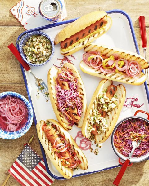 grilled hotdogs with various toppings on a white tray with blue trim