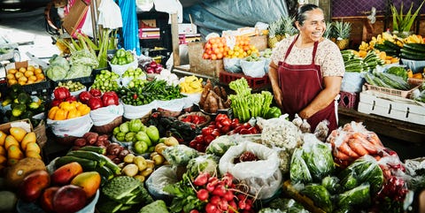 Laughing female produce vendor working at stand in marketplace Laughing female produce vendor working at stand in marketplace