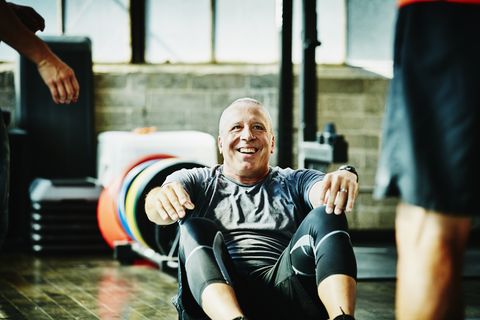 laughing mature man doing crunches during workout