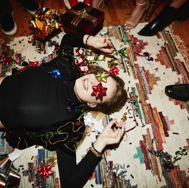 laughing woman lying on floor with bows over eyes during holiday party with friends
