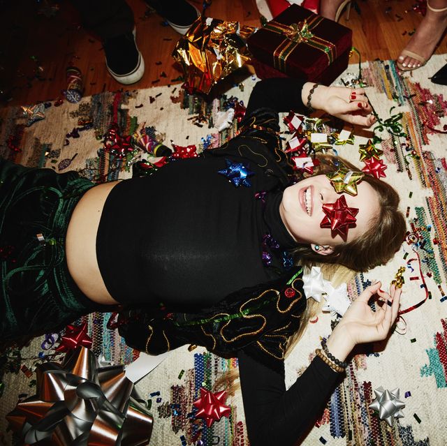 laughing woman lying on floor with bows over eyes during holiday party with friends