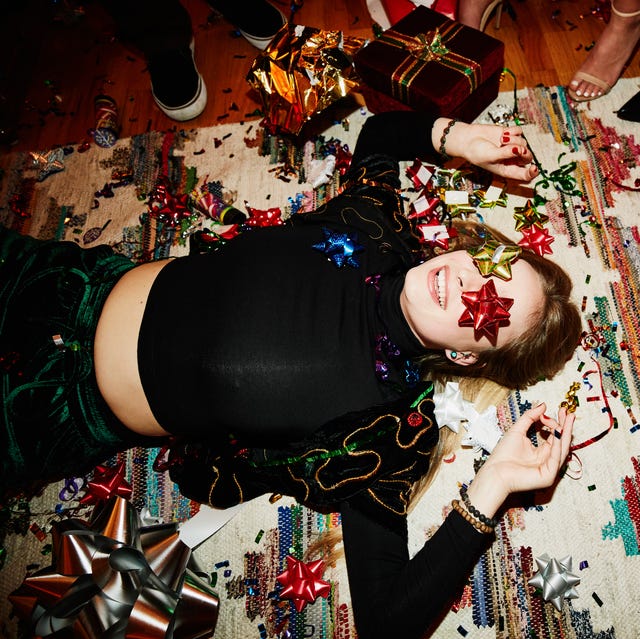 laughing woman lying on floor with bows over eyes during holiday party with friends