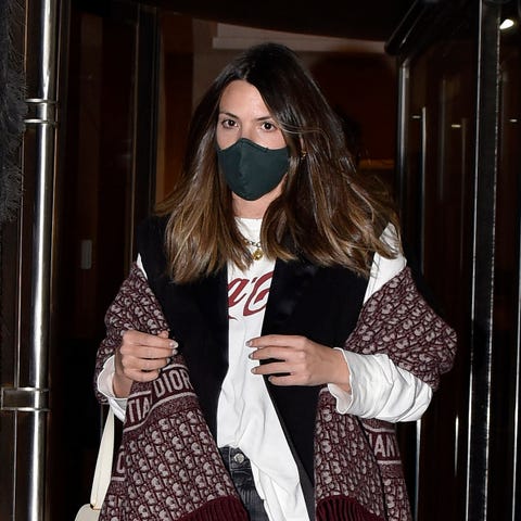 laura matamoros por la calle con pelo suelto, mascarilla negra y poncho granate de christian dior