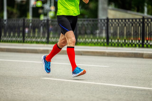 legs male runner in bright red compression socks run down street race