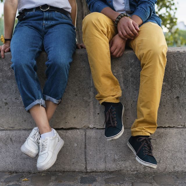 legs of a couple sitting on a wall