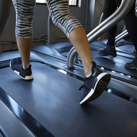 Legs of woman walking on treadmill in gym