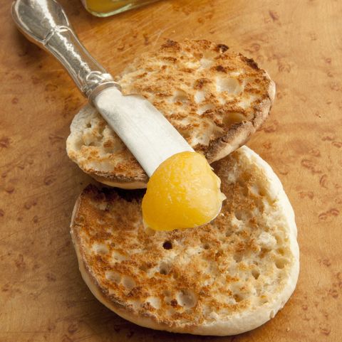 Lemon curd being spread on an English muffin
