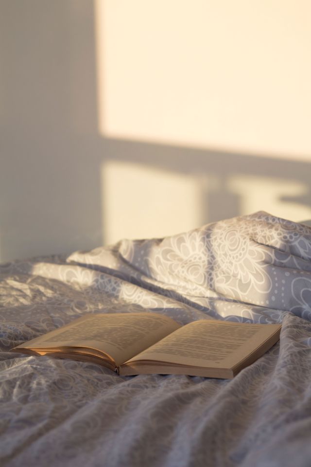 libro su letto con luce del sole che entra da finestra