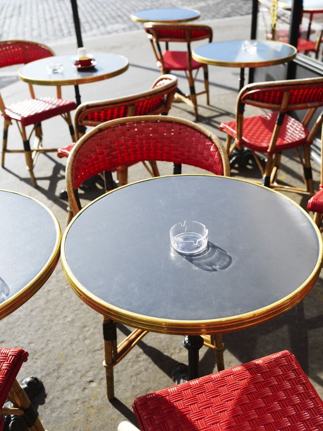 france, paris, sunlit tables and chairs outside a cafe in paris street