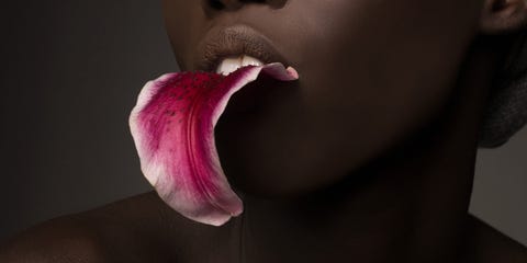 a woman sticking her tongue out with a flower petal