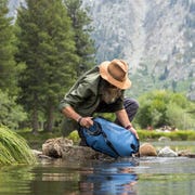 man filling up the lifestraw gravity filter in a river