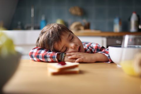 a little boy sleeping during his breakfast