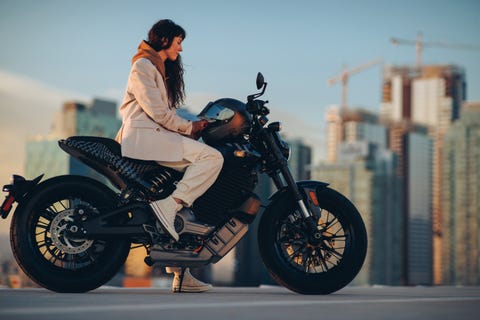 arka planda şehir silüeti ile park edilmiş livewire s2 del mar elektrikli motosiklet üzerinde oturan kadın