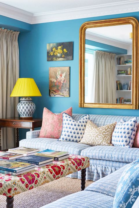blue living room with large gilt mirror and yellow lampshade