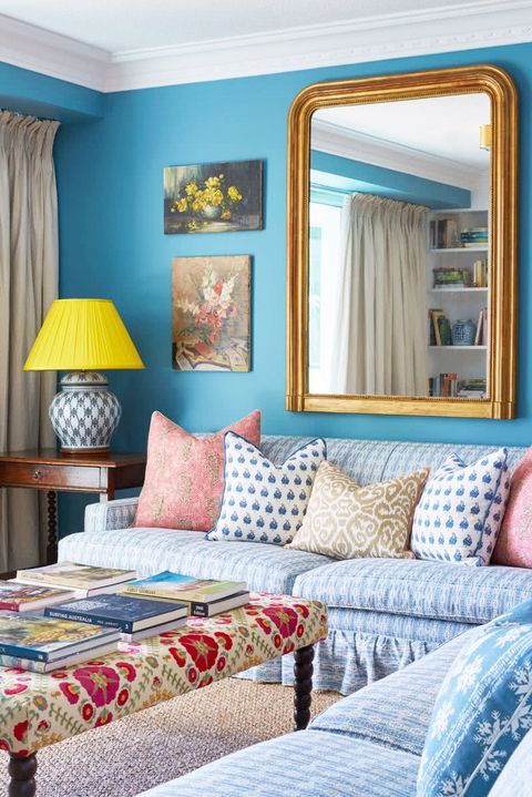 blue living room with large gilt mirror and yellow lampshade
