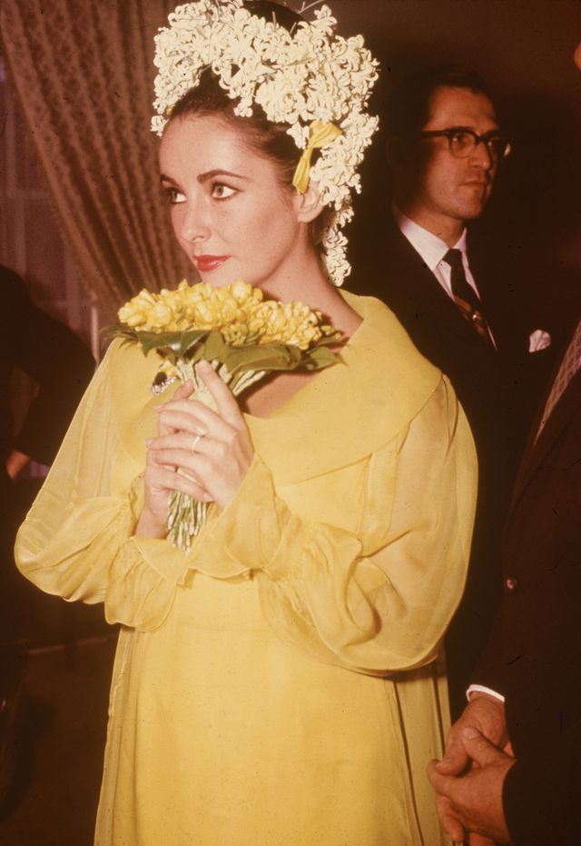 british born actor elizabeth taylor, a yellow dress and floral headdress, holds a bouquet of flowers at her wedding to actor richard burton, march 15, 1964 photo by hulton archivegetty images