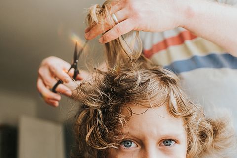 hombre cortando pelo a niño con pelo rizado