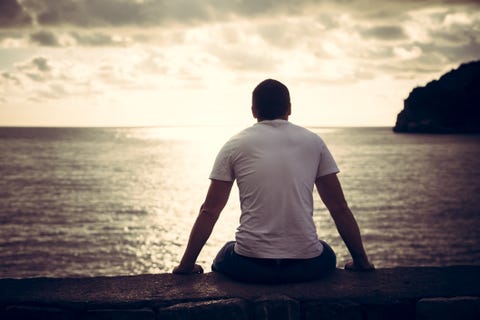 Eenzame mens die met hoop horizon met zonlicht tijdens zonsondergang met effect van licht aan het eind van tunnel bekijken Lonely man looking with hope at horizon with sunlight during sunset with effect of light at the end of tunnel