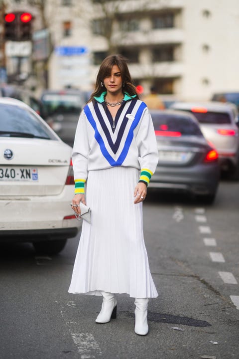  paris, france 03 mars clara berry porte un pull lacoste à col en v rayé bleu noir et blanc avec poignets colorés, une jupe plissée blanche, une pochette, des bottes blanches, à l'extérieur de lacoste, lors de la fashion week de paris automne-hiver 20202021 le 03 mars 2020 à paris, france photo de edward berthelotgetty images