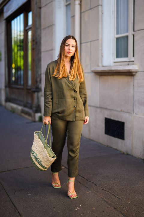 paris, france april 23 maria rosaria rizzo lacoquetteitalienne wears gold earrings, a gold chanel chain pendant necklace, a khaki quartier libre blazer jacket and matching suit pants, a green and beige wicker fuchsia handbag, green leather and gold chain strappy bottega veneta sandals shoes, on april 23, 2021 in paris, france photo by edward berthelotgetty images