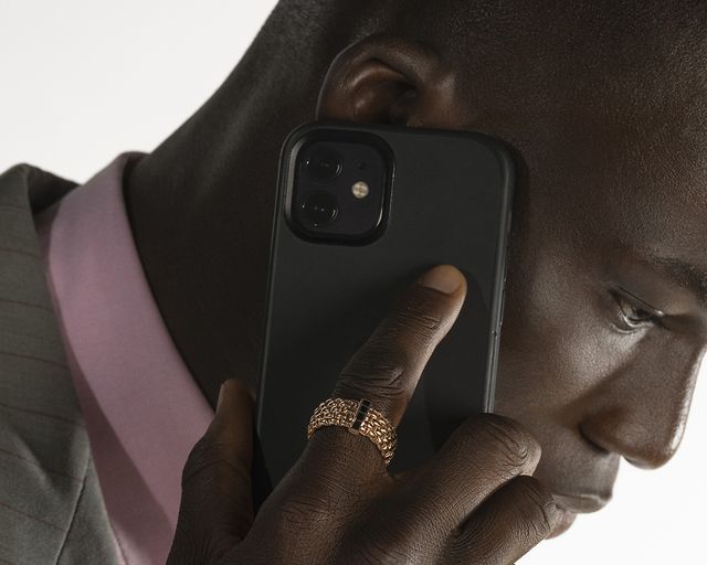 man holding mobile phone wearing a gold ring