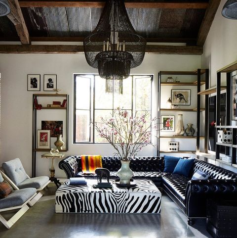 living room with large tufted leather wraparound sofa open shelves and a zebra design square coffee table with art objects on it