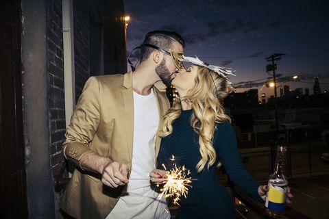 loving young couple burning sparklers while kissing on balcony