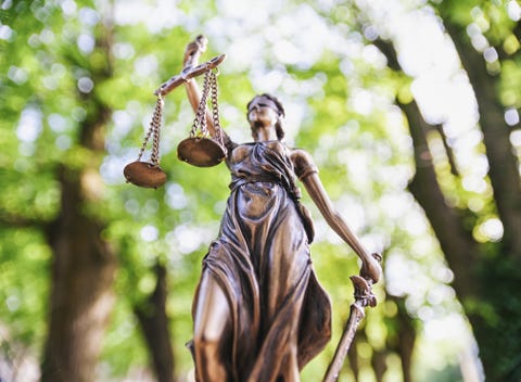 Low Angle View Of Lady Justice Against Trees