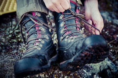 Low section of female hiker tying laces of hiking boots