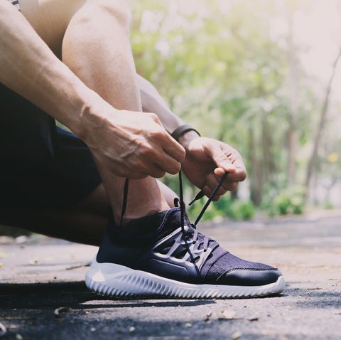 Low Section Of Man Tying Shoelace On Road