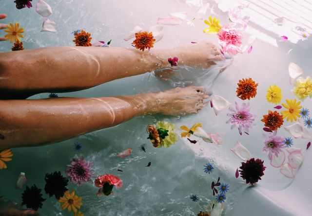 piernas de mujer rodeadas de flores en el agua