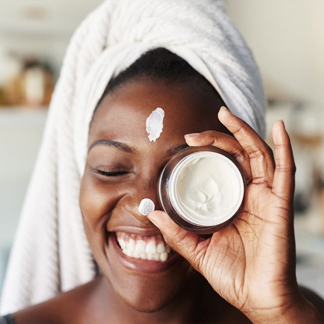 black woman holding face cream
