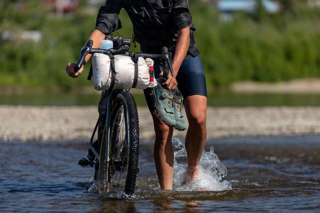 a person walking a bike through water