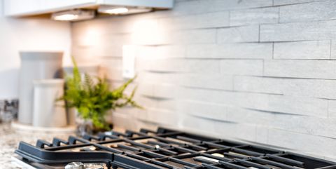 macro closeup of modern luxury gas stove top with tiled backsplash