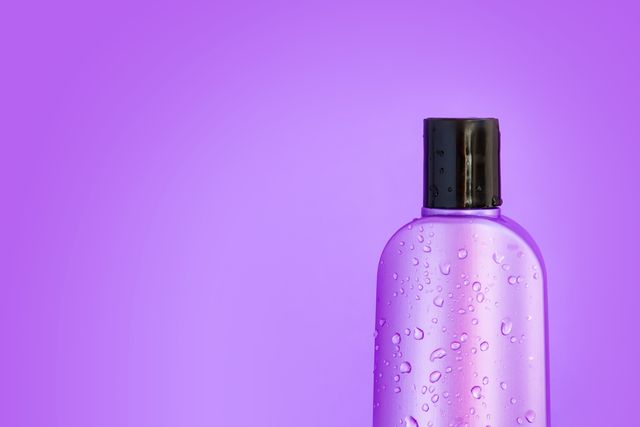 macro cosmetic purple wet bottle on a purple background horizontal copy space