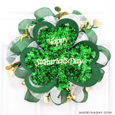 wreath made out of green tinsel, ribbon, burlap and more shaped like a shamrock, with gold letters reading happy st patrick's day