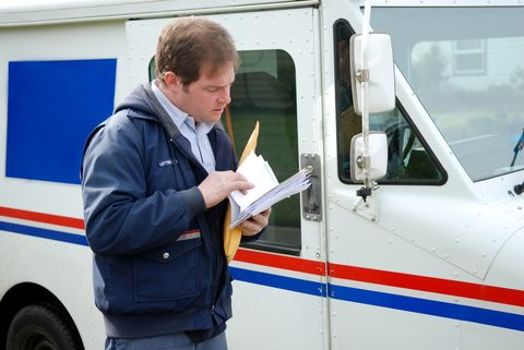 Mail carrier sorting mail near delivery truck