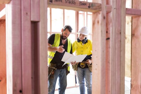 Male and female construction workers discuss the building plans inside the building site