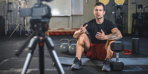 Male Athlete Sitting on Exercise Mat and Making Vlog at Gym