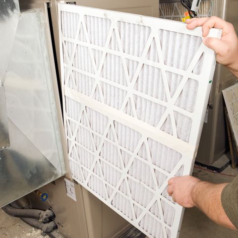 male hands change large pleated furnace air filter