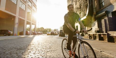Male messenger cycling along city street