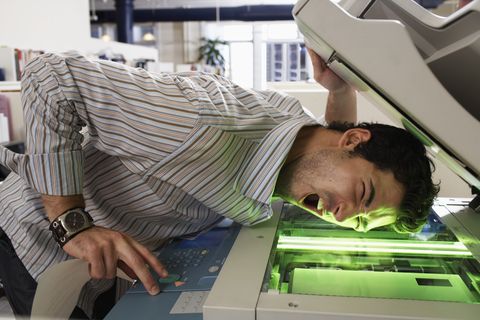Male office worker photocopying side of face, mouth open, eyes closed