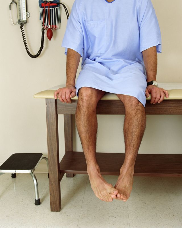 male patient sitting on examining room table, mid section