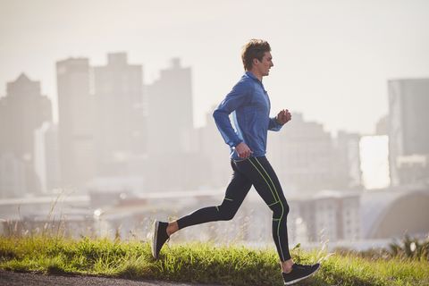 Male runner running on sunny urban street