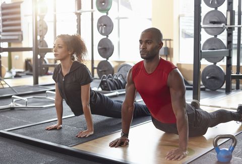 Man and woman doing yoga stretch in a gym
