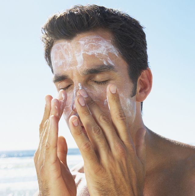 man applying sun block or suntan lotion to face