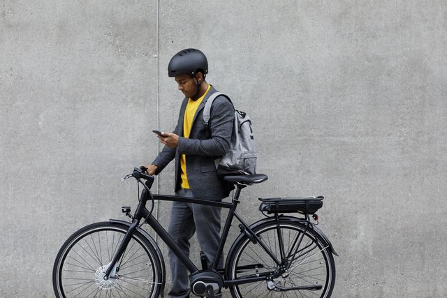 Young man standing by electric bicycle using smartphone