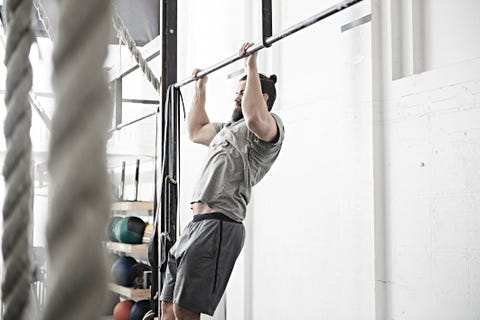 Uomo che fa chin-up nella palestra di cross training