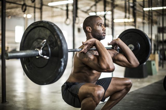 man voert barbell front squat uit in de gym